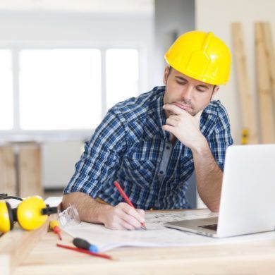 Man in hard hat with plans and laptop